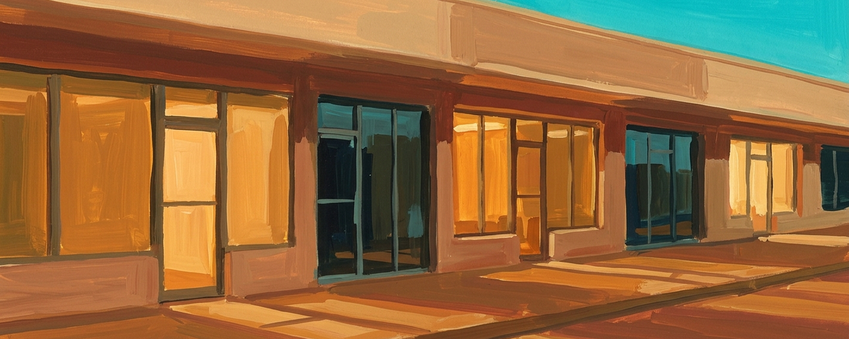 Modern storefront with orange and tan exterior, large windows, and turquoise sky reflecting Lake Havasu...